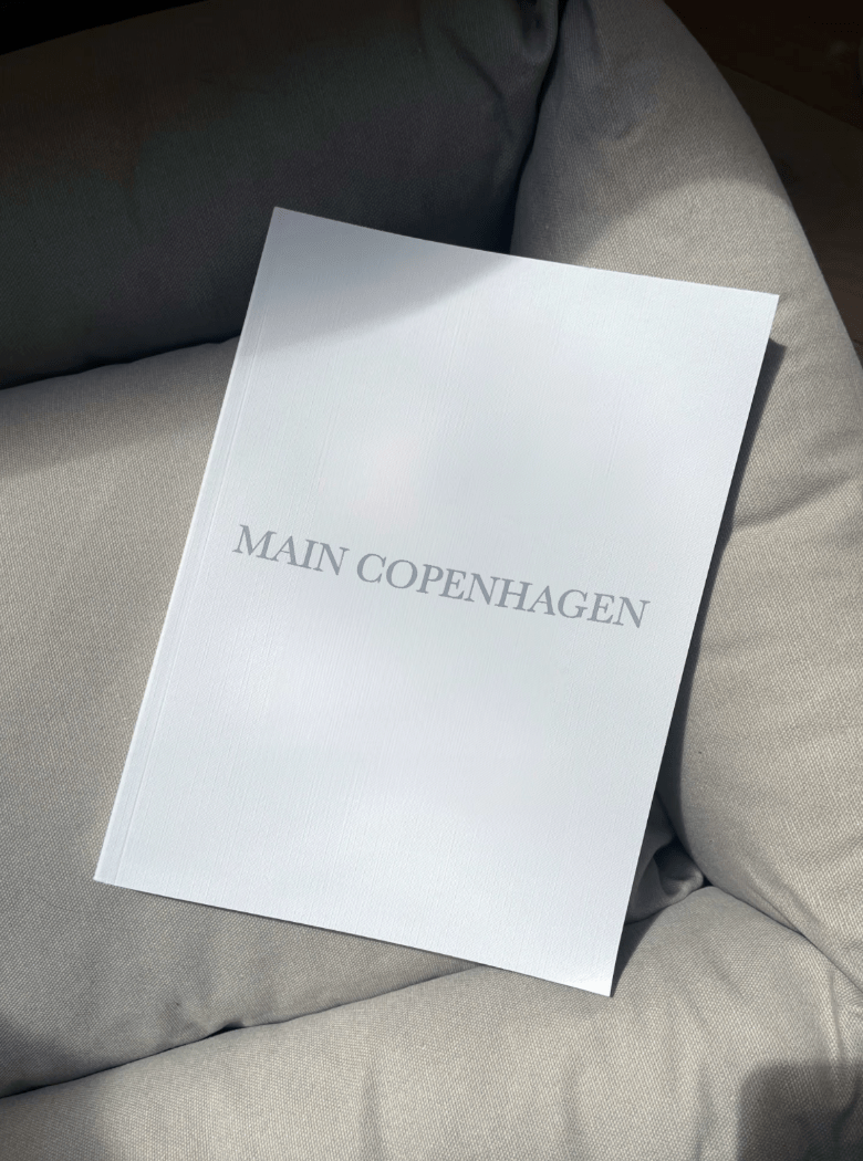 Main Copenhagen gavekort visualiseret i fysisk form som ligger i en komfortabel grå sofa
